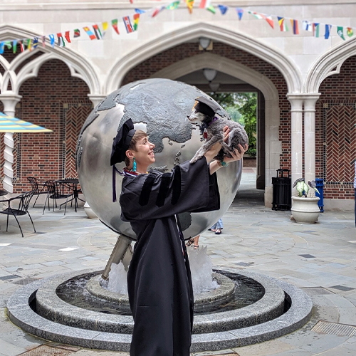 Law school graduate in a cap and gown with her dog.